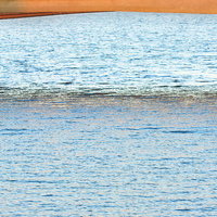 夕方の川岸で釣りをする釣り人と街並みの写真