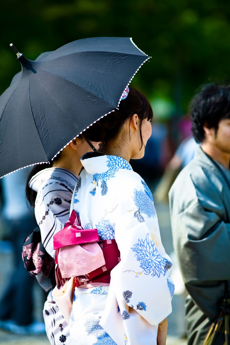 黒い日傘をさす浴衣姿の女性の後ろ姿