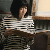 カフェで写真集を眺めるボーダーシャツの女性の写真