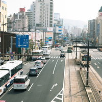 長崎駅前の大通りを走る路面電車と都市風景の写真
