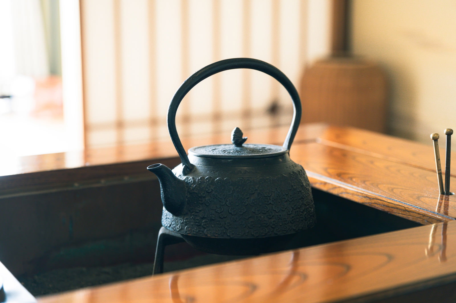 畳の上に置かれた黒い鉄製の茶釜と囲炉裏