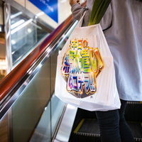 エコバッグを持ってエスカレーターに乗る買い物客の女性の写真