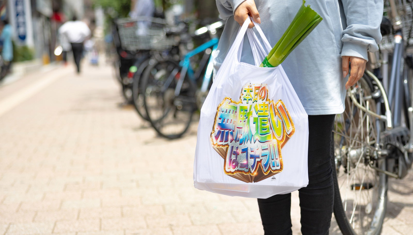 カラフルなデザインの白いエコバッグを持つ人の手