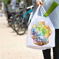 カラフルなデザインのエコバッグを持って買い物をするの写真