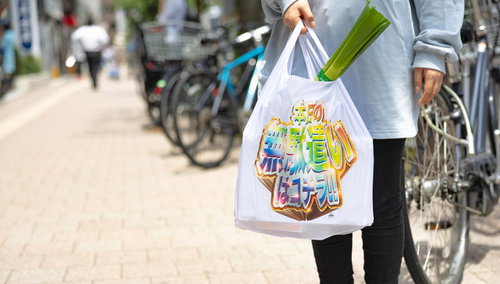 カラフルなデザインのエコバッグを持って買い物をする