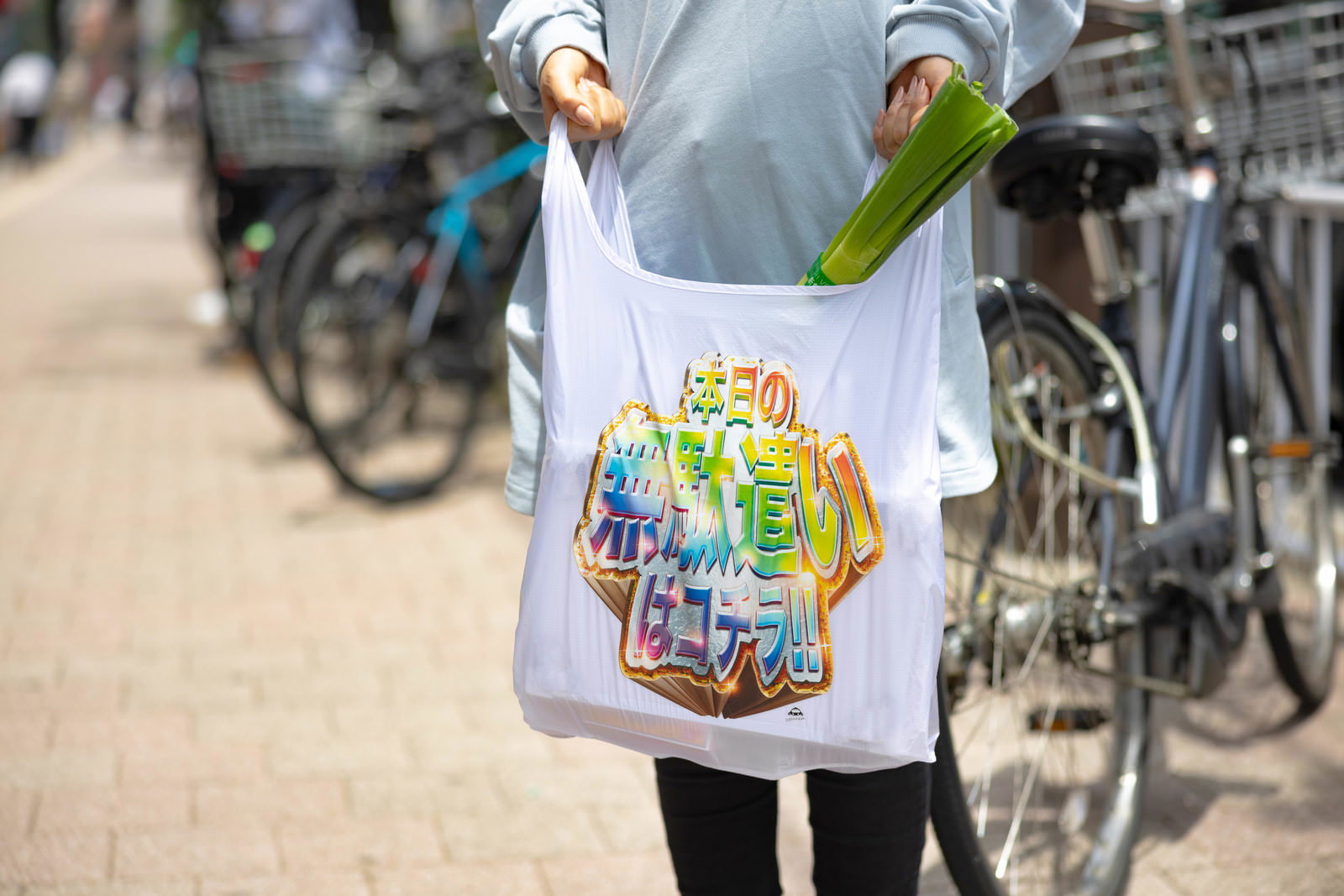 カラフルなイラスト入りエコバッグを持って街中を歩く人