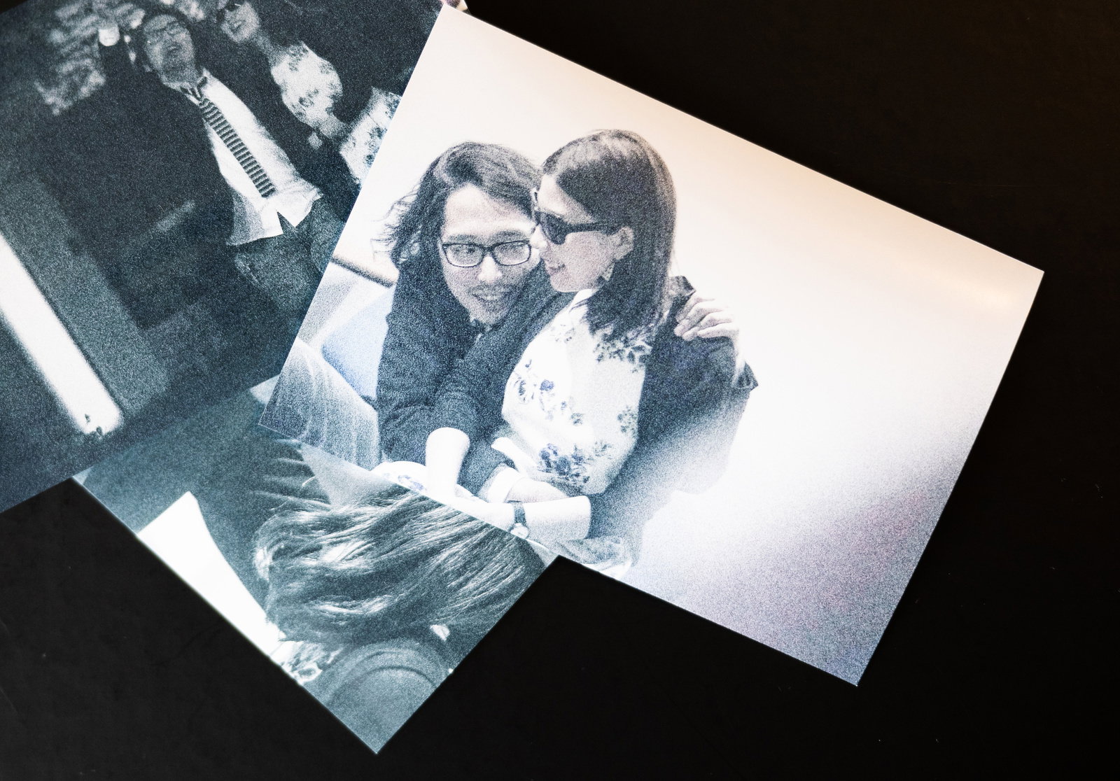 テーブルの上に重ねて置かれた複数のモノクロ写真［モデル：ゆうせい］