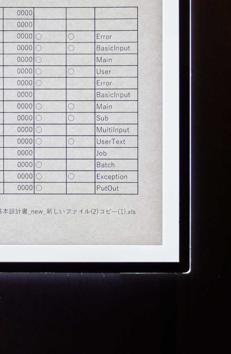 黒いバインダーファイルに挟まれた白い紙の業務資料