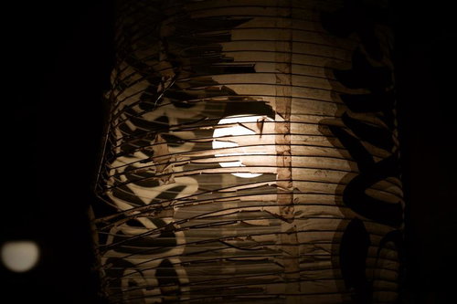 破れた和紙の隙間から光が漏れる古びた提灯