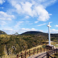 ありま展望台の丘の上に立つ白い十字架と自然豊かな山々の写真