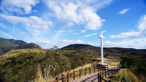 ありま展望台の丘の上に立つ白い十字架と自然豊かな山々