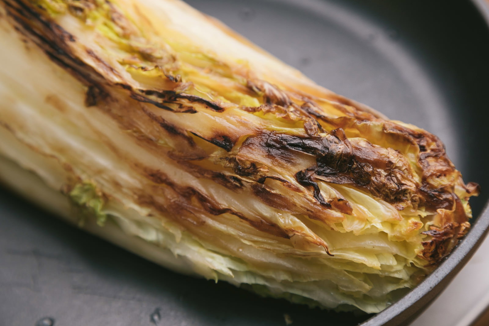 黒い丸皿に盛った焼き色つきの白菜
