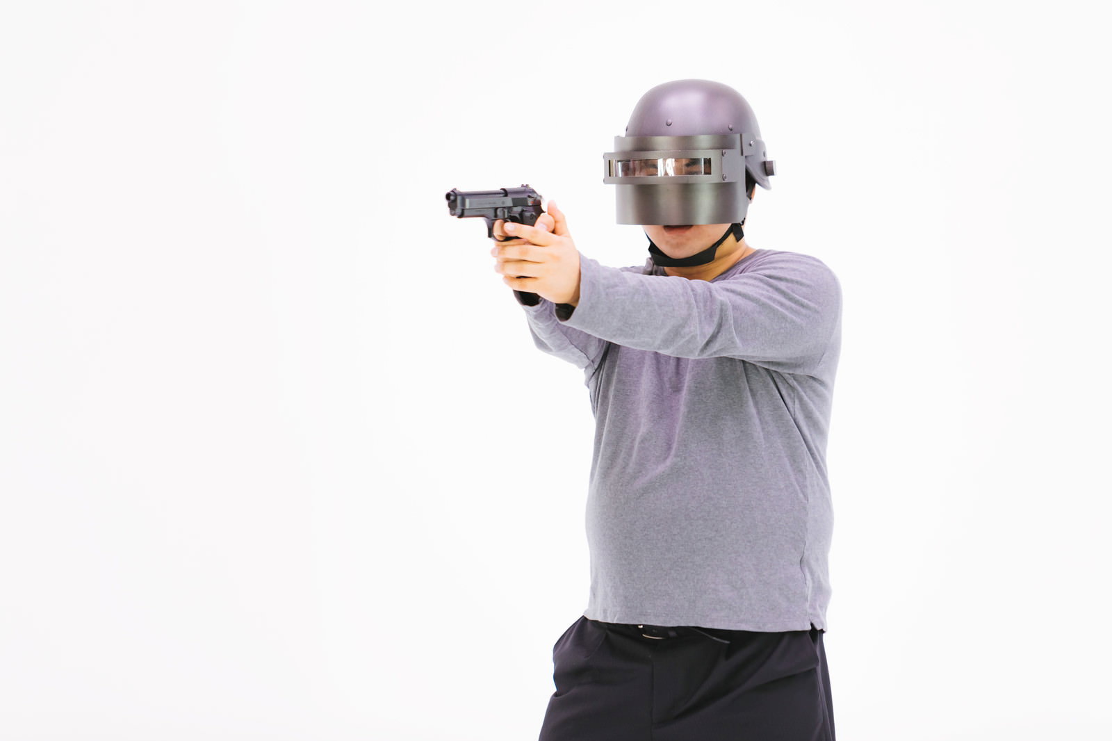 ヘルメットを着用し両手で拳銃を構える男性［モデル：段田隼人］