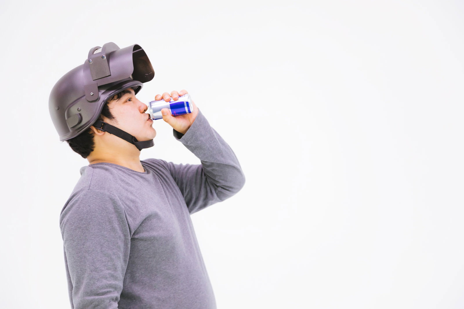 エナジードリンクを飲むグレーの服を着た男性［モデル：段田隼人］