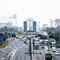 トラックやバスが走る工業地帯の片側3車線の幹線道路の写真