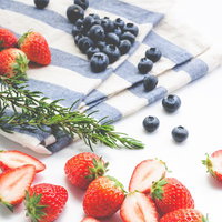 白い布の上に散らばるイチゴとブルーベリーの写真