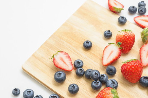 木製まな板に並べたイチゴとブルーベリーのカットフルーツ