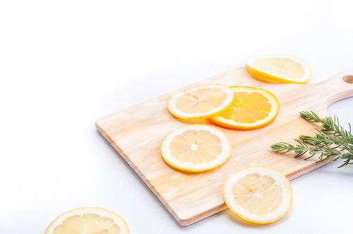 木製まな板の上のおしゃれなカットレモンとローズマリー