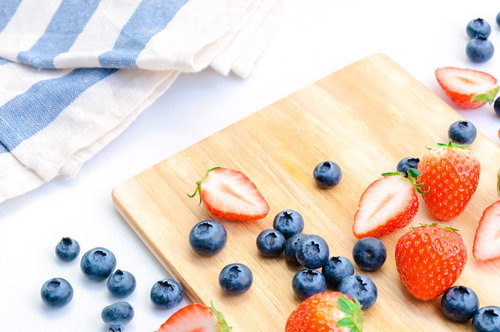 木製カッティングボードに並ぶ甘いイチゴとブルーベリー
