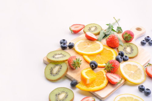 白いマット背景に並べたカットフルーツとベリーのミックス