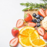 まな板の上に色とりどり並ぶカットフルーツと果物の写真