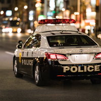 繁華街を巡回するパトカーの後姿の写真