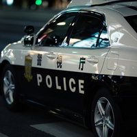 警察車両に映るネオンと夜の街の風景 夜間巡回パトカーの写真