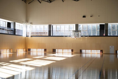 自然光が差し込むふたば未来学園の体育館、バスケットボールゴール設置