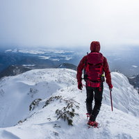 上州武尊山の雪の稜線を歩く赤いウェアの登山者の写真