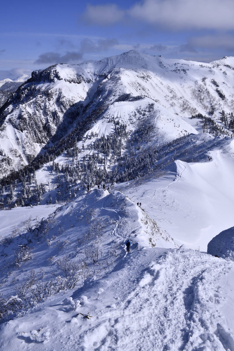 雪に覆われた上州武尊山の山稜を歩く登山者の後ろ姿