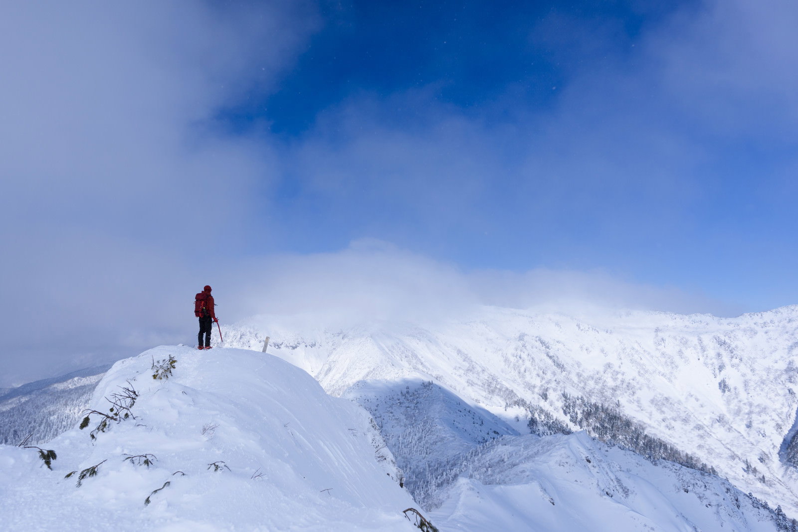 雪に覆われた上州武尊山の山頂付近で青空を背景に立つ登山者