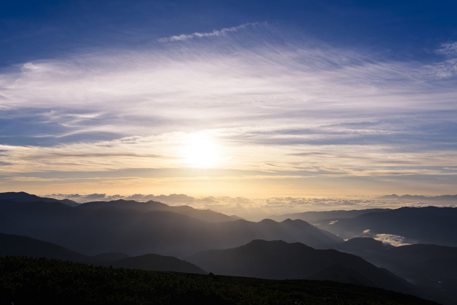 乗鞍岳の山々に朝日が差し込み、雲海と空がオレンジ色に染まっている風景