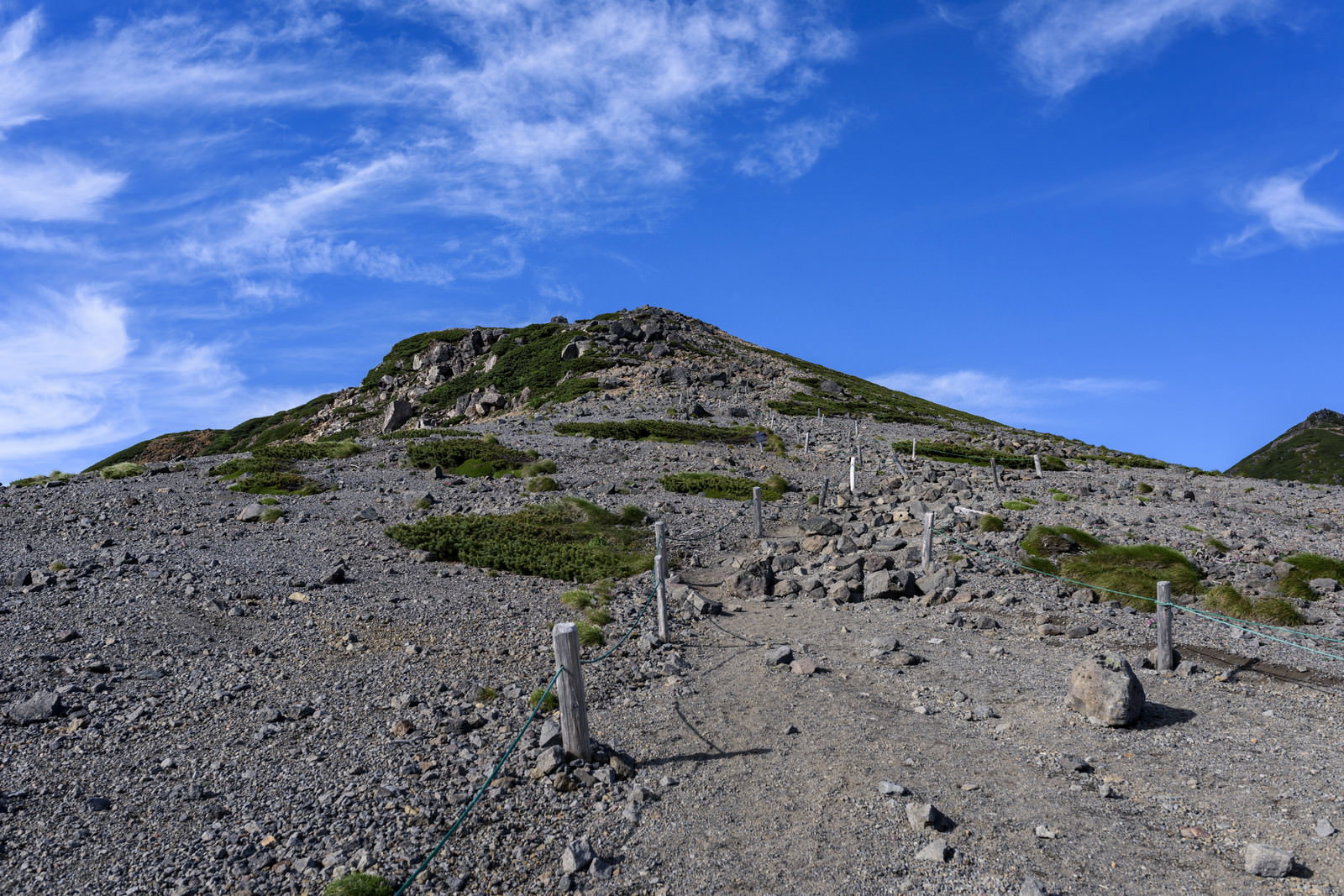 青空の下、乗鞍岳の岩がちな稜線に続く登山道