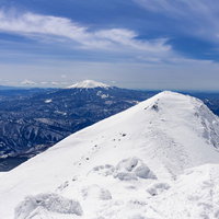 乗鞍岳山頂から眺める雪化粧の御嶽山と青空の写真