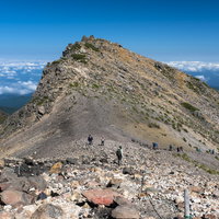 乗鞍岳山頂へと向かう登山者たちの登山道と青空の景色の写真