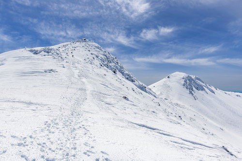 乗鞍岳の雪山、山頂へと続く登山トレースと青空