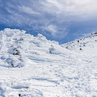 冬の乗鞍岳山頂を目指す登山者と青空の雲、積雪景色の写真