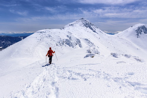 冬の乗鞍岳を登る赤いウェアの登山者の足跡