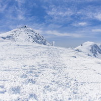 雪に埋もれた指導標と乗鞍岳の山頂の冬景色の写真