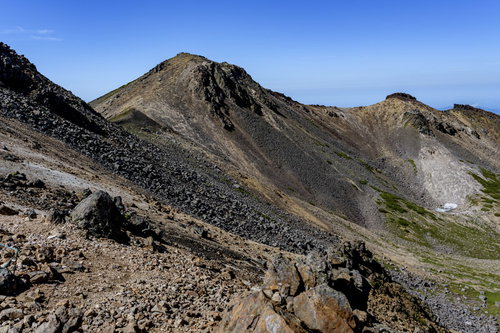 青空の下、岩だらけの乗鞍岳稜線を歩く登山者の風景