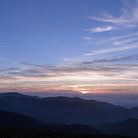 日の出を迎える乗鞍岳の朝焼けの空と山並みのシルエットの写真