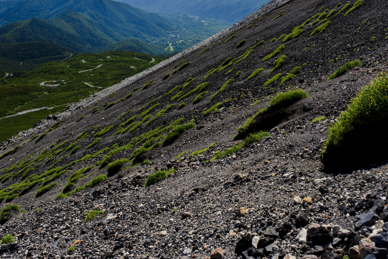 岩石が散らばる乗鞍岳の斜面と遠景の山々