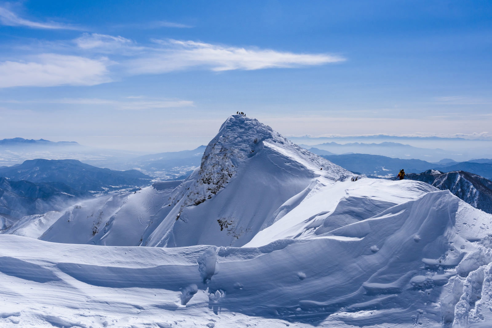 青空の下、雪に覆われた谷川岳のトマの耳を登山道から撮影した風景