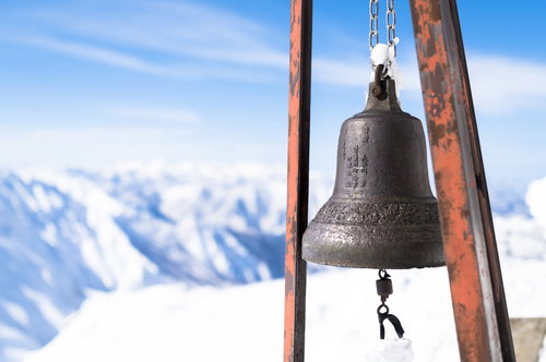 雪化粧した谷川岳を背景にした山小屋の鐘と谷川連峰