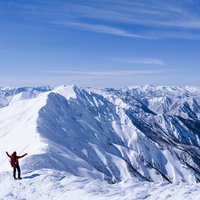 谷川岳の雪山頂上で両手を上げて歓喜する登山者の写真