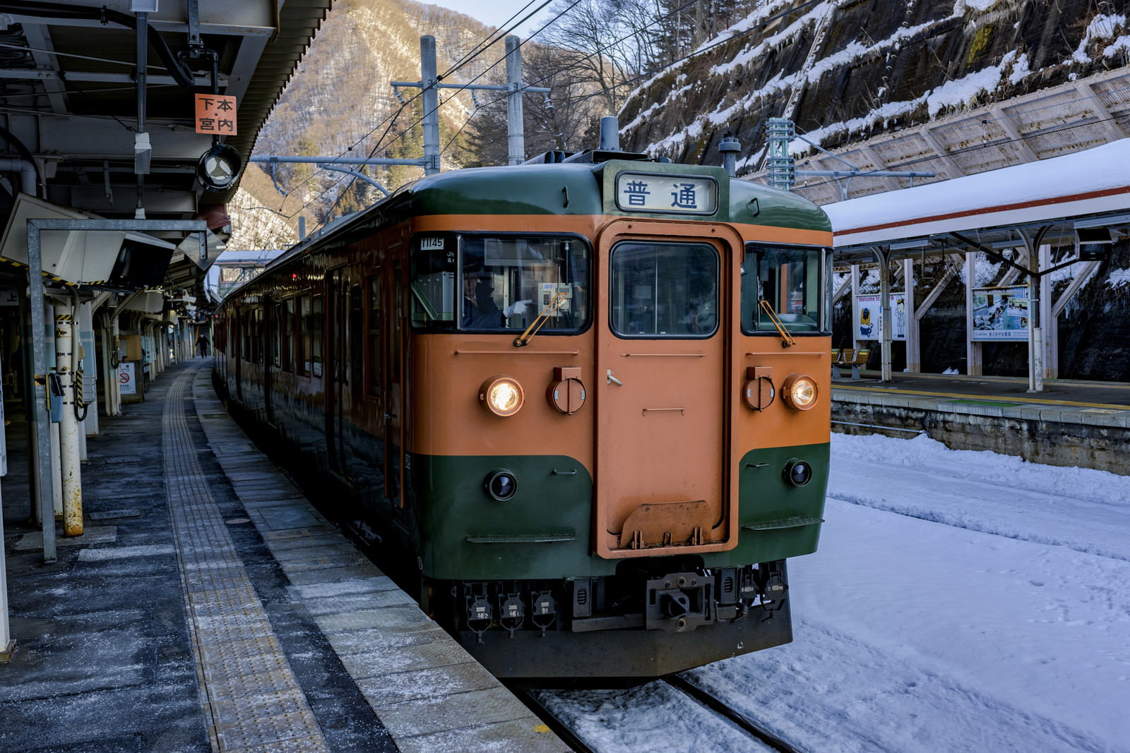 水上駅のホームに停車するオレンジと緑の電車