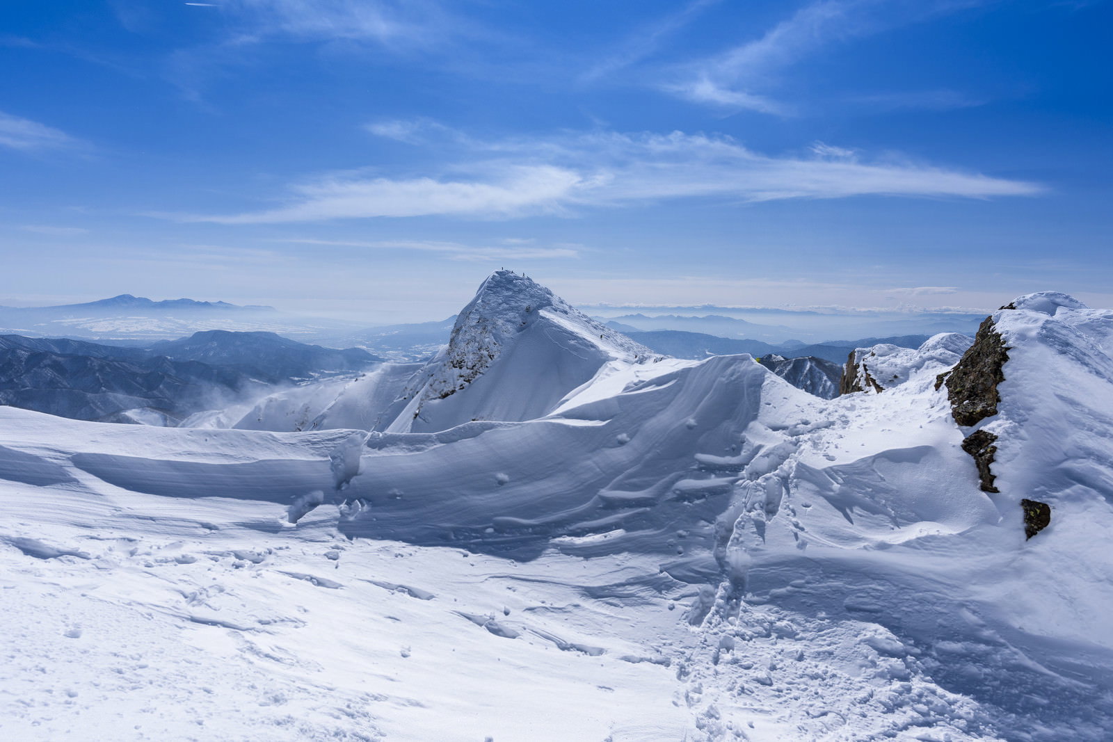 雪化粧した谷川岳トマノ耳を背景に立つ登山者
