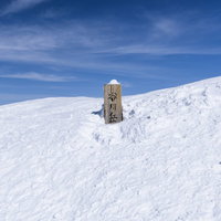 真っ白な雪に埋まった谷川岳山頂標と青空の絶景の写真