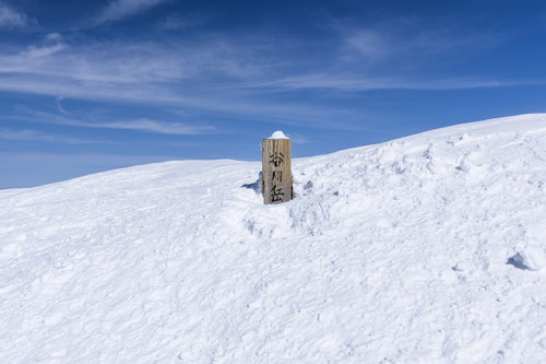 真っ白な雪に埋まった谷川岳山頂標と青空の絶景