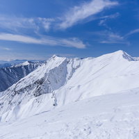 青空の下に広がる谷川主脈の雪稜線の写真